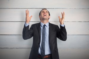 Stressed businessman gesturing against painted blue wooden planks